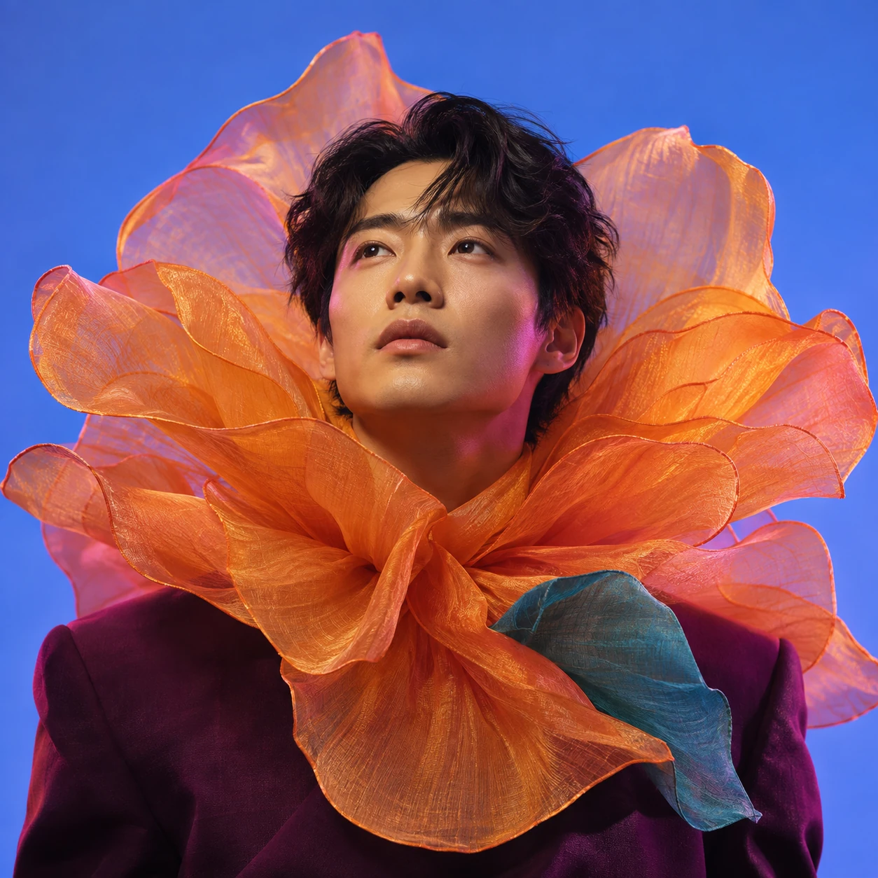 An original editorial portrait of a man with an orange petal collar against vivid blue.
